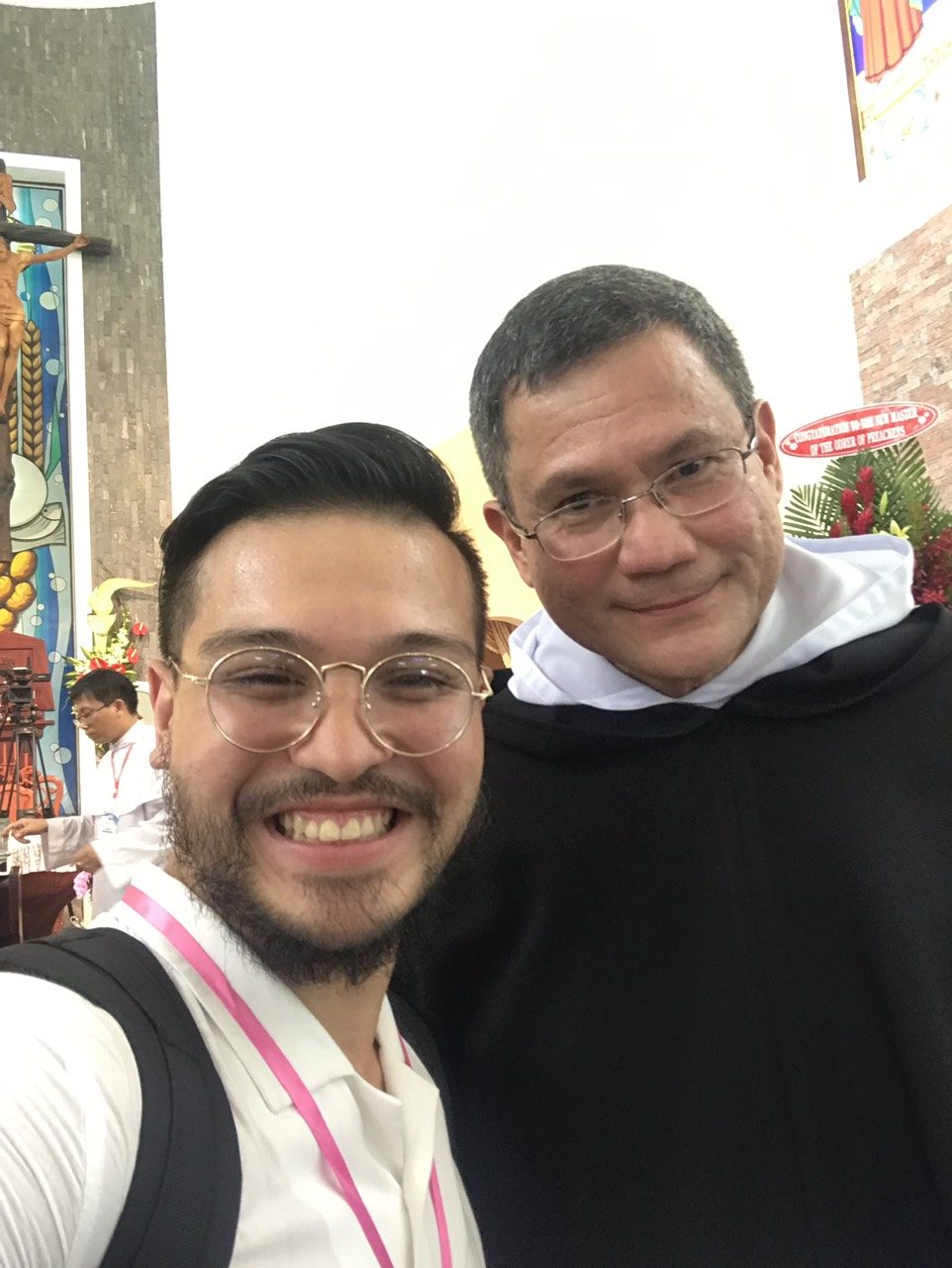 Selfie of a smiling Benz Rodil with Fr. Gerard Timoner III, OP, wearing the black Dominican cappa inside a church