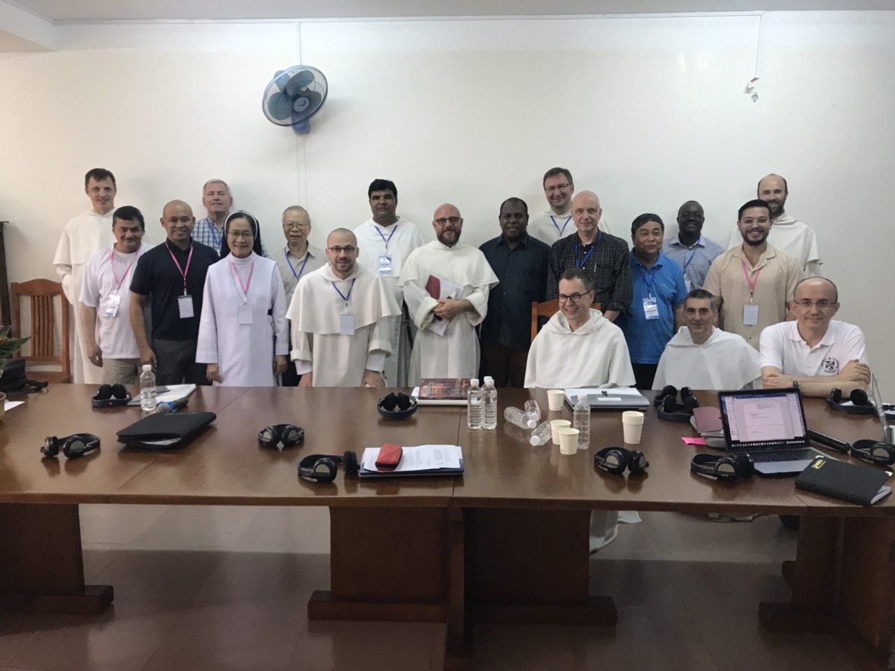 Members of Commission 5, Dominican friars, a sister and lay delegates, posing around a long conference table with headsets and water bottles